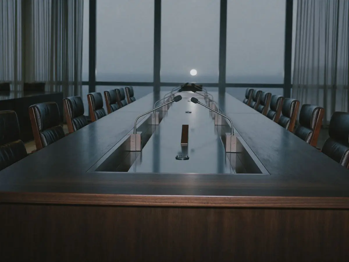 Empty international hearing room with a long conference table and microphones