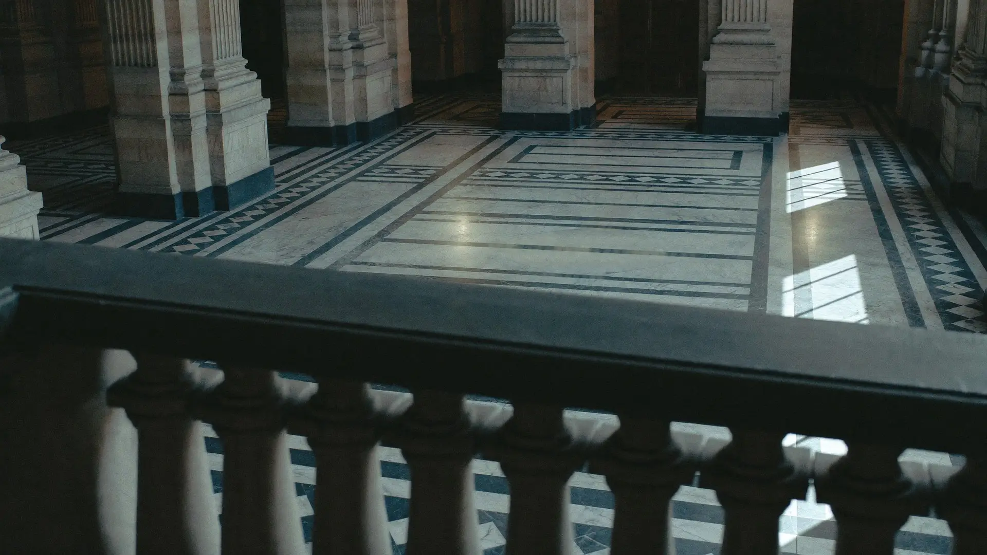 Stone gallery balustrade overlooking an empty marble hall in an institutional building